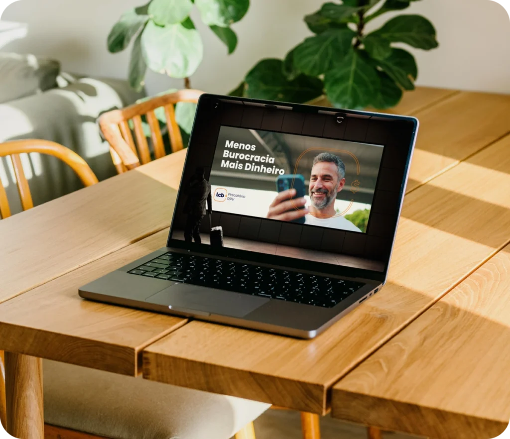 Laptop aberto com tela exibindo vídeo sobre "Menos Burocracia, Mais Dinheiro" do LCbank.